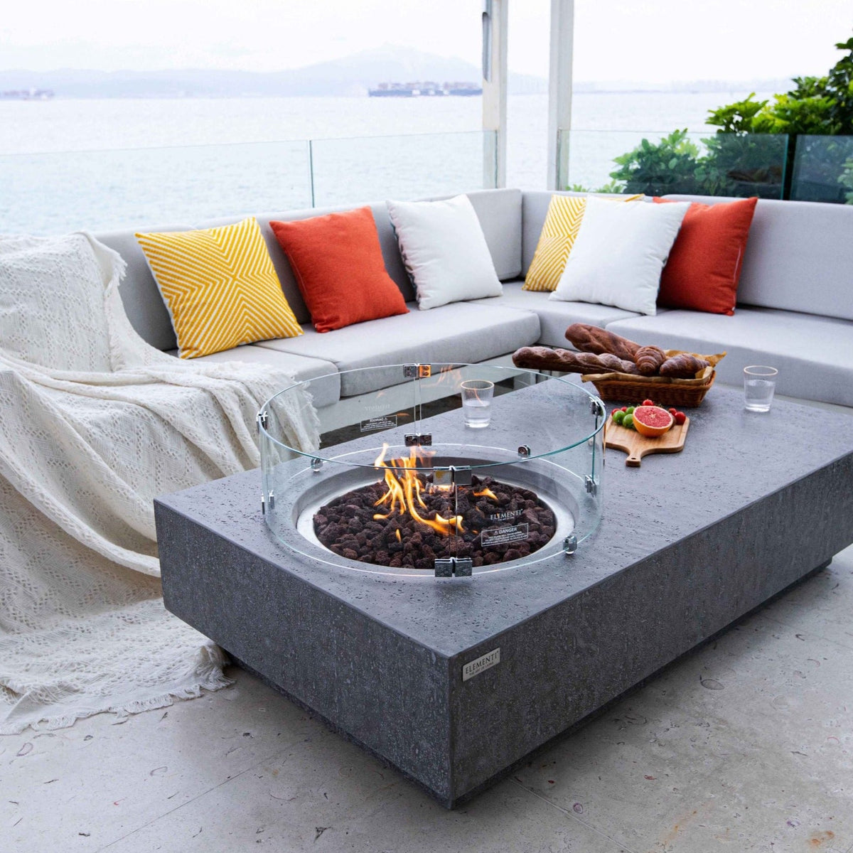 Elementi Metropolis Fire Pit Table in Light Gray lit in a balcony with view