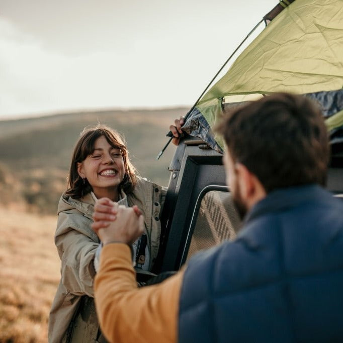 couple enjoying the outdoors next to tent on truck bed